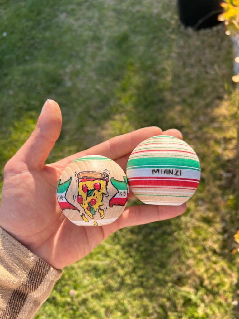 Mano sujetando dos tamas de kendama pintadas a mano