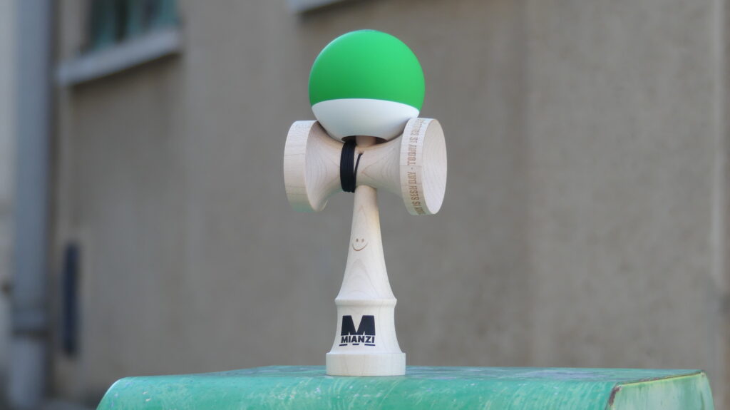 Kendama Mianzi con tama verde sobre un muro